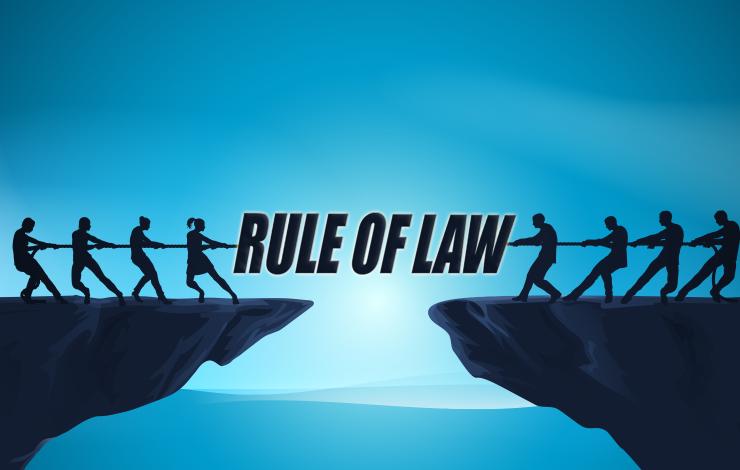Tug of war over cliff with rule of law written between each side